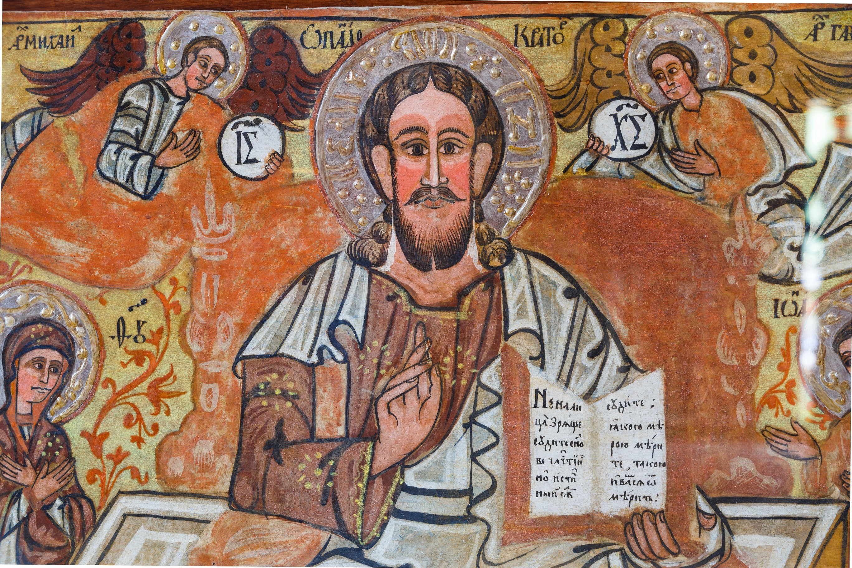 Wizerunek Chrystusa. W lewej dłoni trzyma On otwartą księgę, prawą wykonuje gest błogosławieństwa. Nas Nim dwóch aniołów.